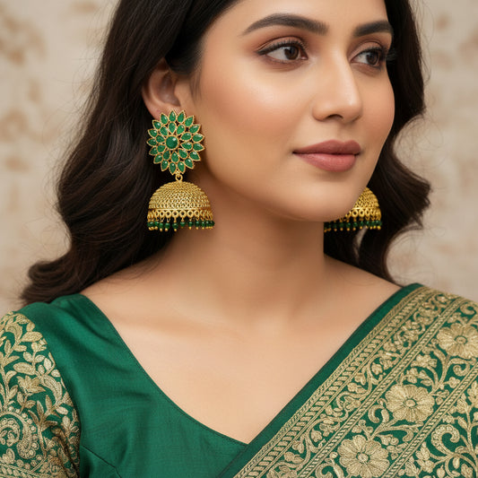 Gold and green floral earrings on a gray stand with a light gray background