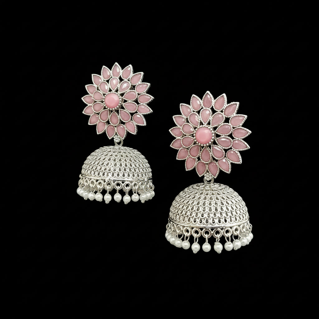 Pair of pink floral earrings with silver and pearl details on a gray stand.