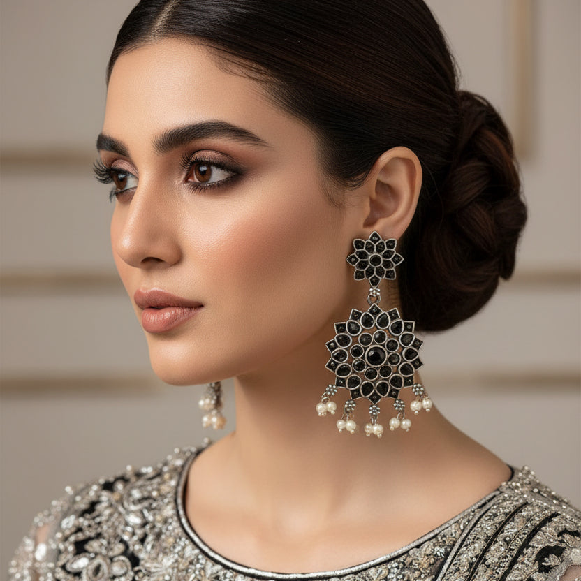Pair of silver earrings with floral designs on a black background