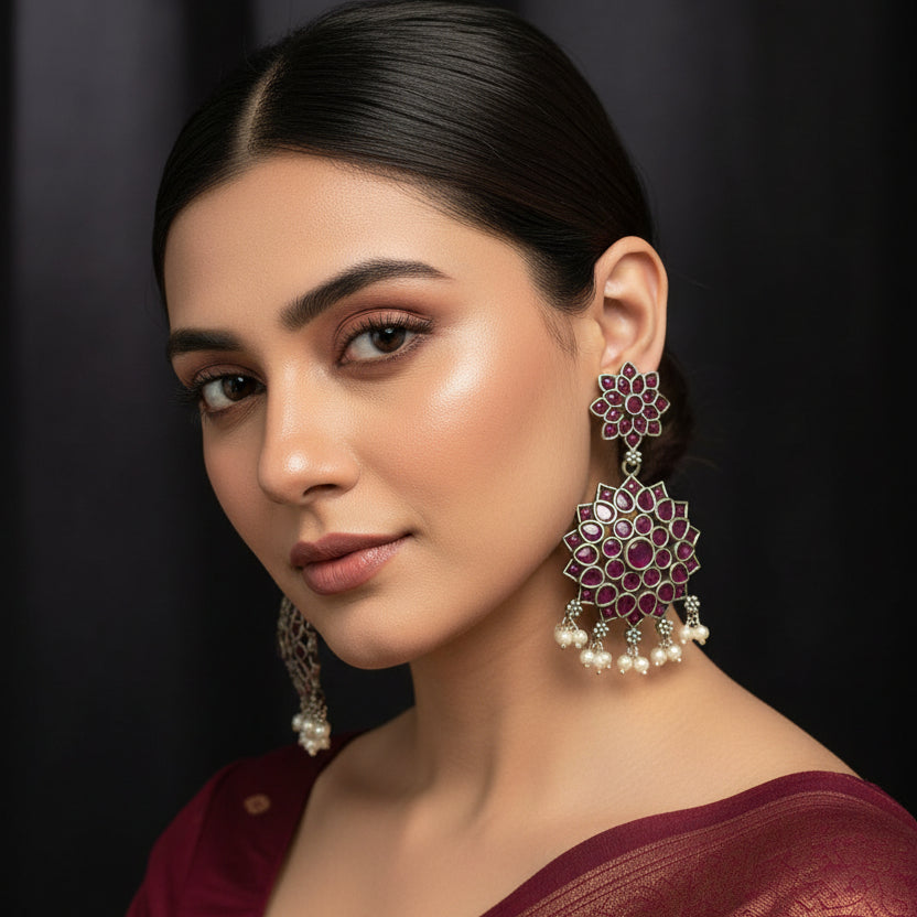 Pair of floral earrings with red gemstones on a black background