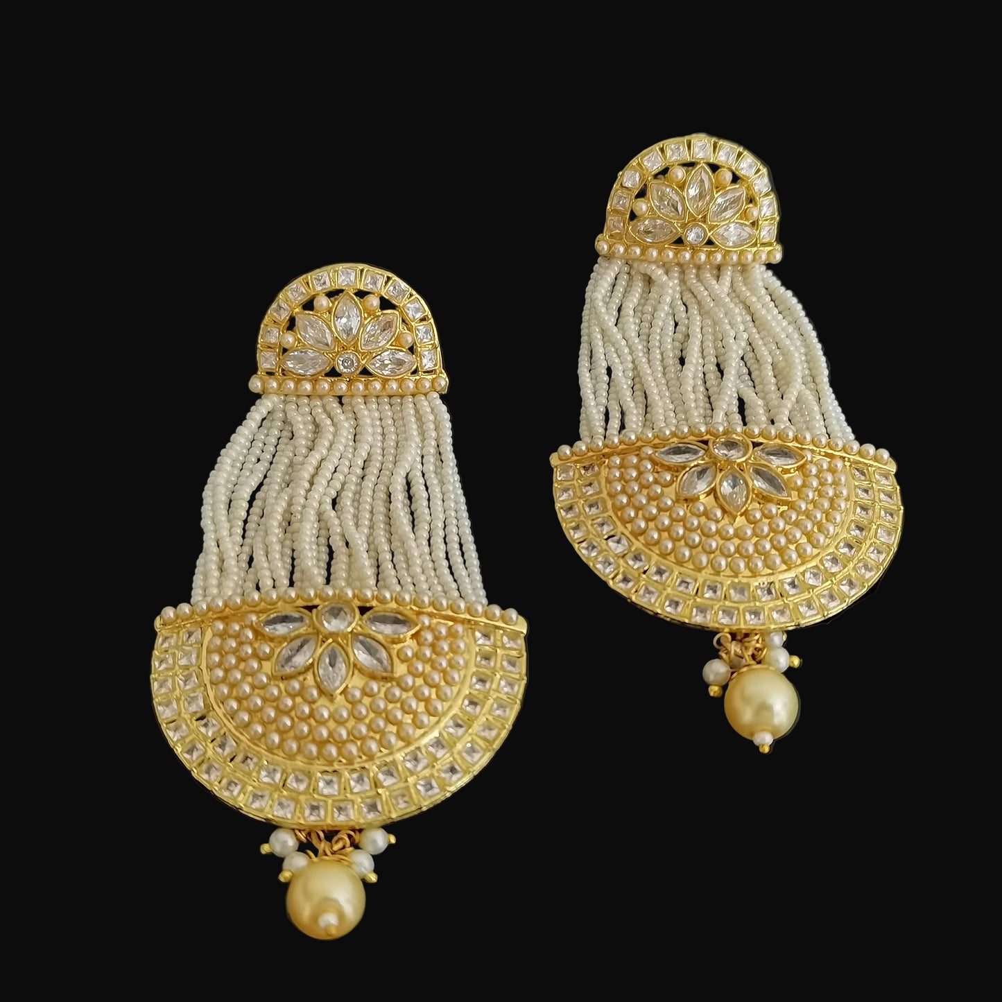Pair of gold and pearl tassel earrings on a black background