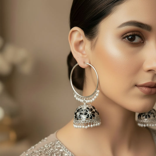 Pair of silver hoop earrings with jhumka designs on a black background
