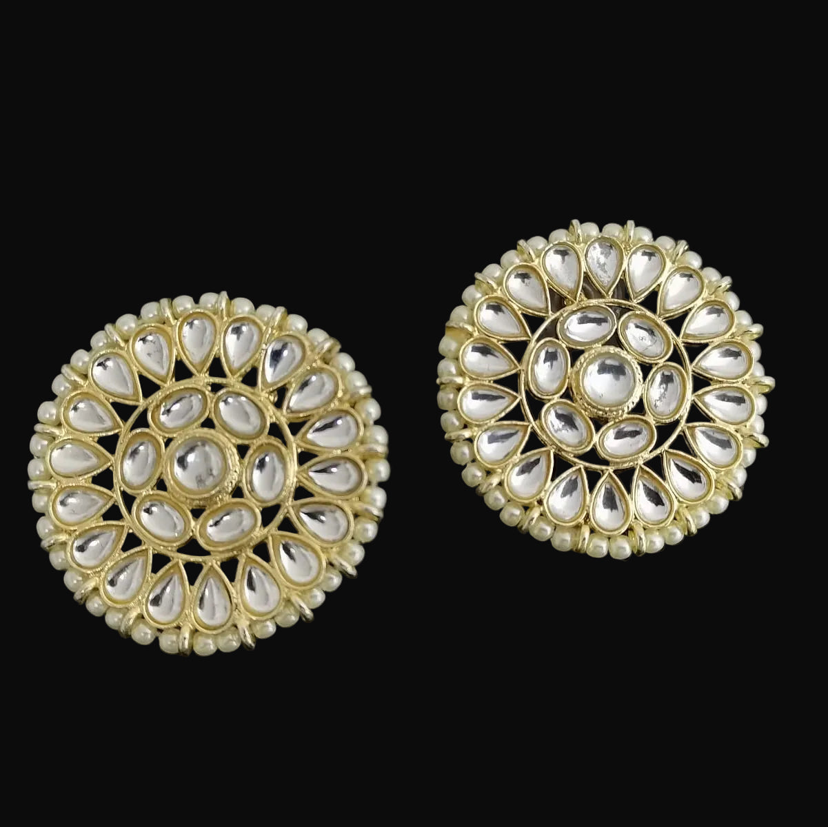 Pair of gold and pearl earrings on a black background