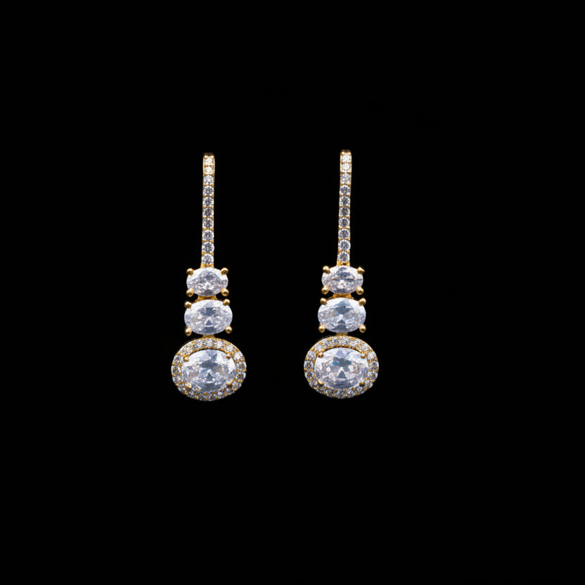 Gold and diamond earrings on a dark background with 'Saheli' branding.
