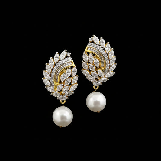 A pair of gold and crystal drop earrings with white pearl dangles, displayed on a black stand against a gray background with the brand name 'SAHELI MY BEST FRIEND' at the top.