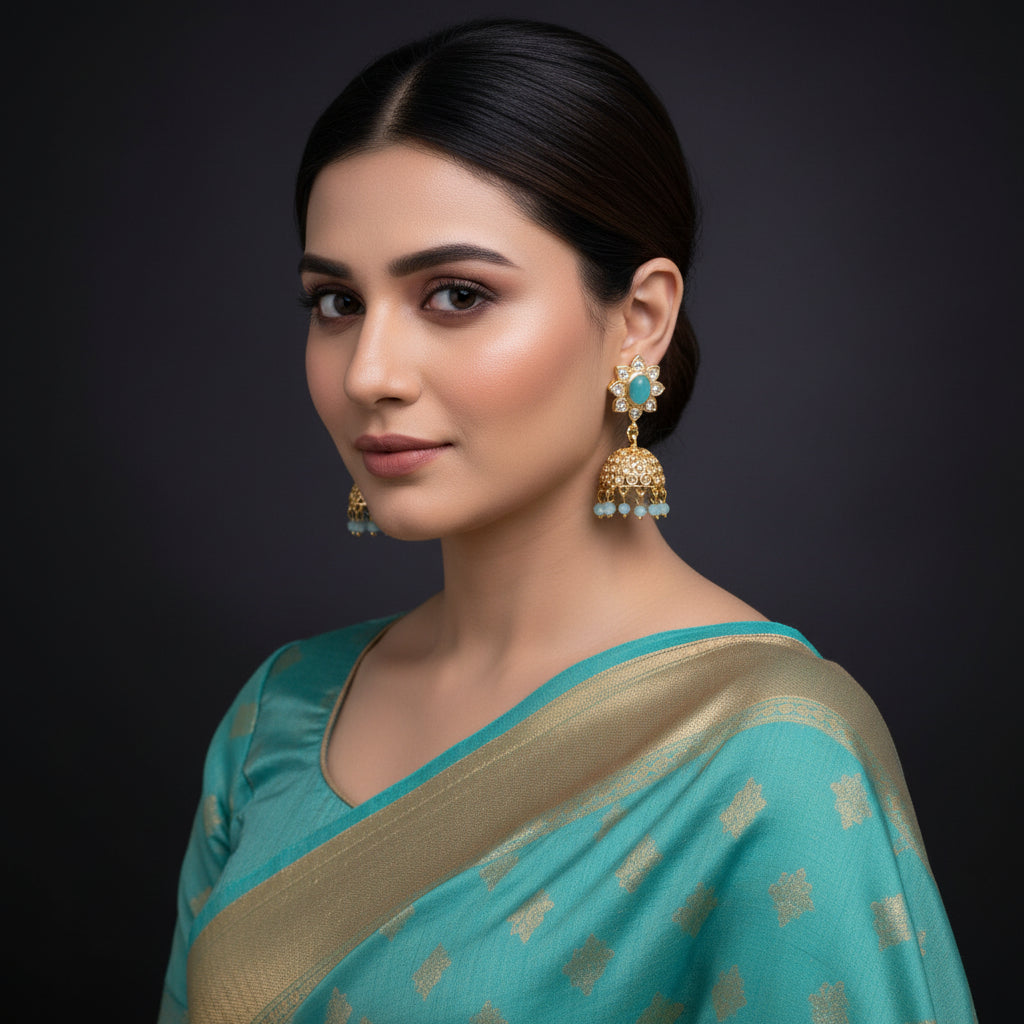 Gold and turquoise earrings on a black stand with 'Saheli' branding.