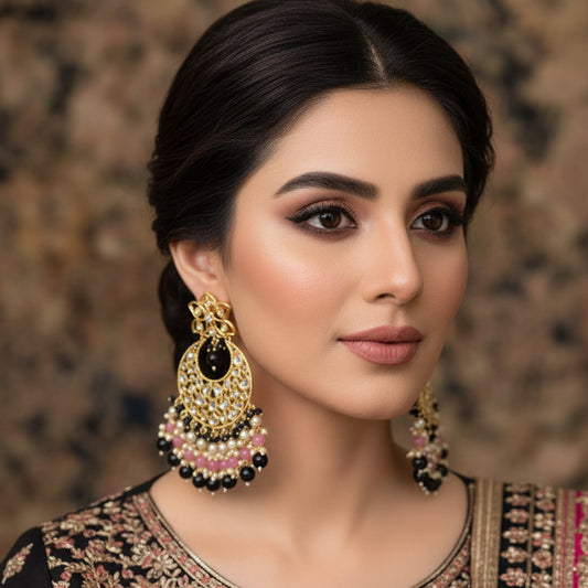 Pair of ornate earrings with black, pink, and gold details on a gray background, featuring the brand 'Saheli'.
