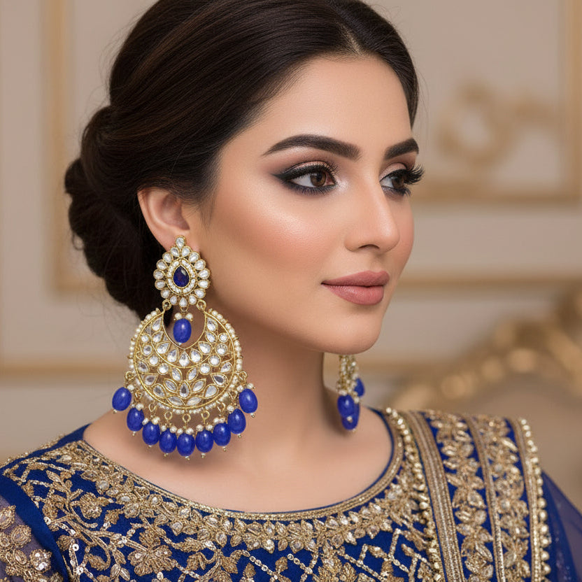 Pair of ornate earrings with blue stones on a dark background