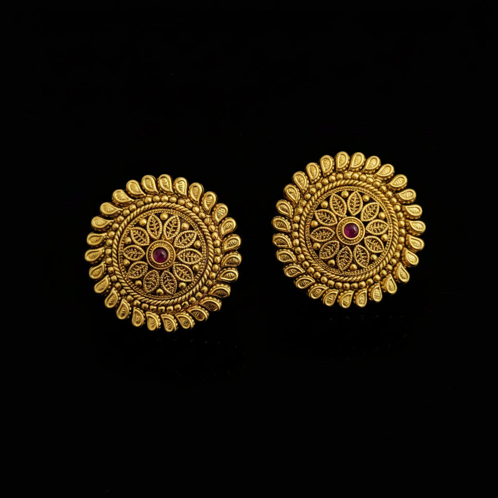 Pair of gold earrings with intricate designs on a dark background
