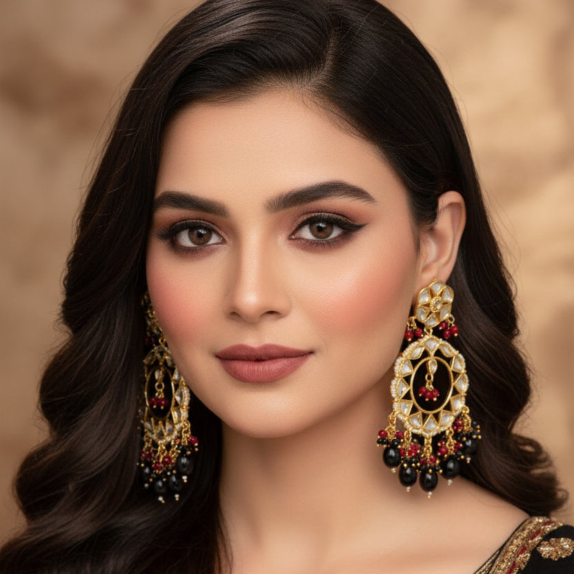 Pair of ornate earrings with black, red, and gold details on a dark background