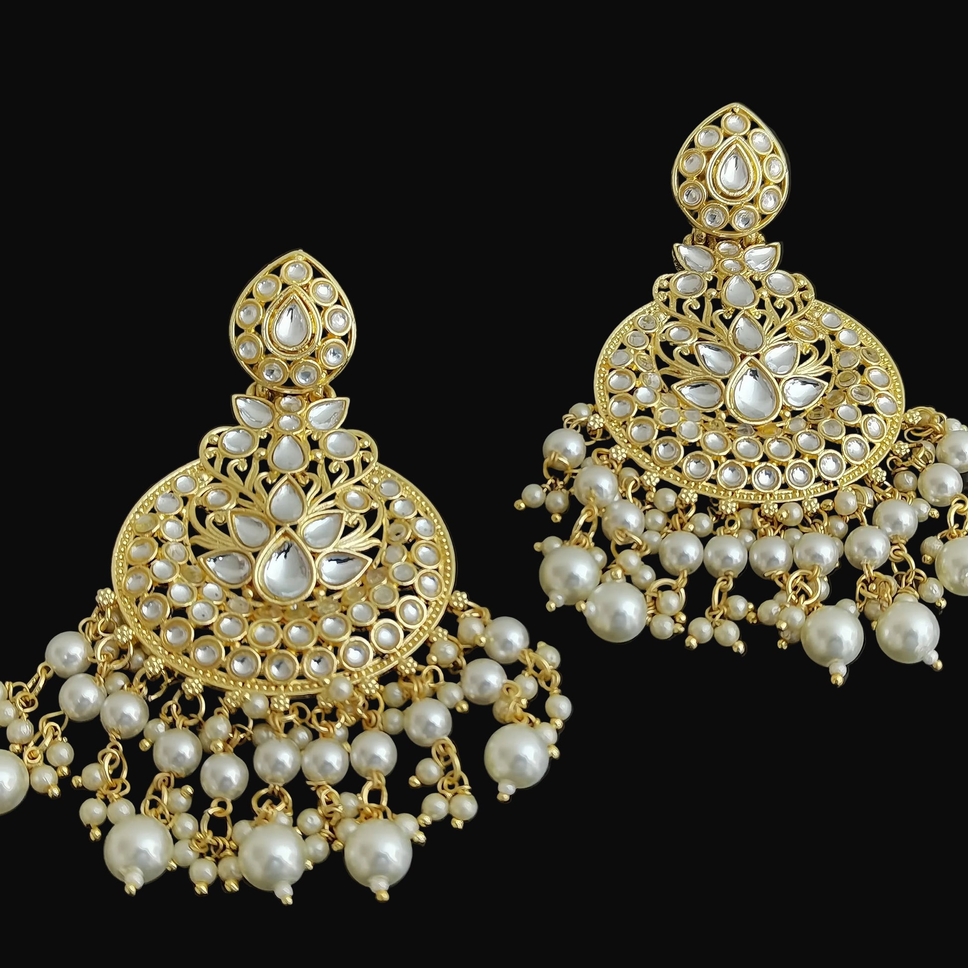 Pair of gold and pearl earrings on a black background