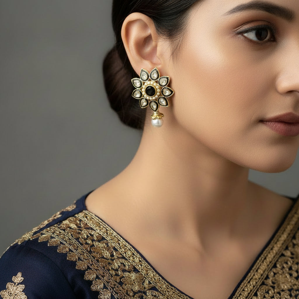 Decorative earrings with gold, blue, and pearl details on a dark background, featuring the brand 'Saheli'.