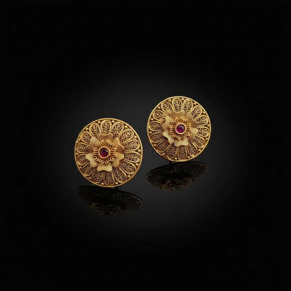 Pair of gold earrings with intricate designs on a black background