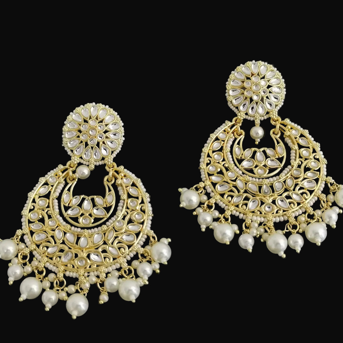 Pair of gold and pearl earrings on a black background