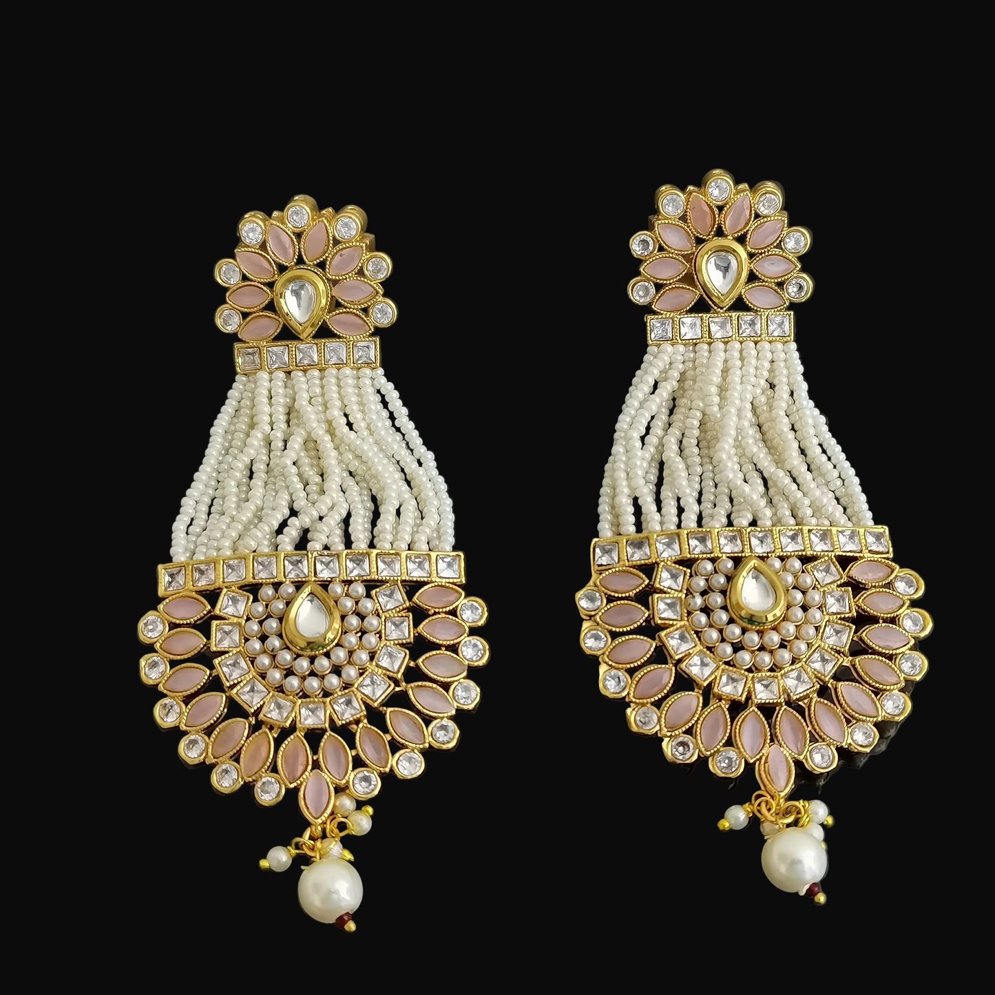 Pair of ornate earrings with gold and pearl details on a dark background
