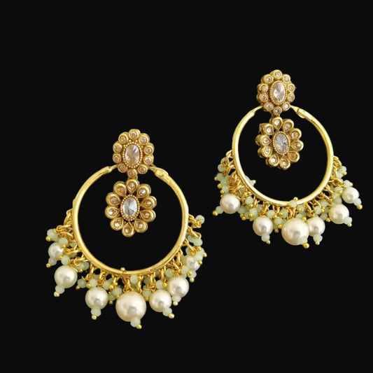 Gold earrings with pearl accents on a dark background