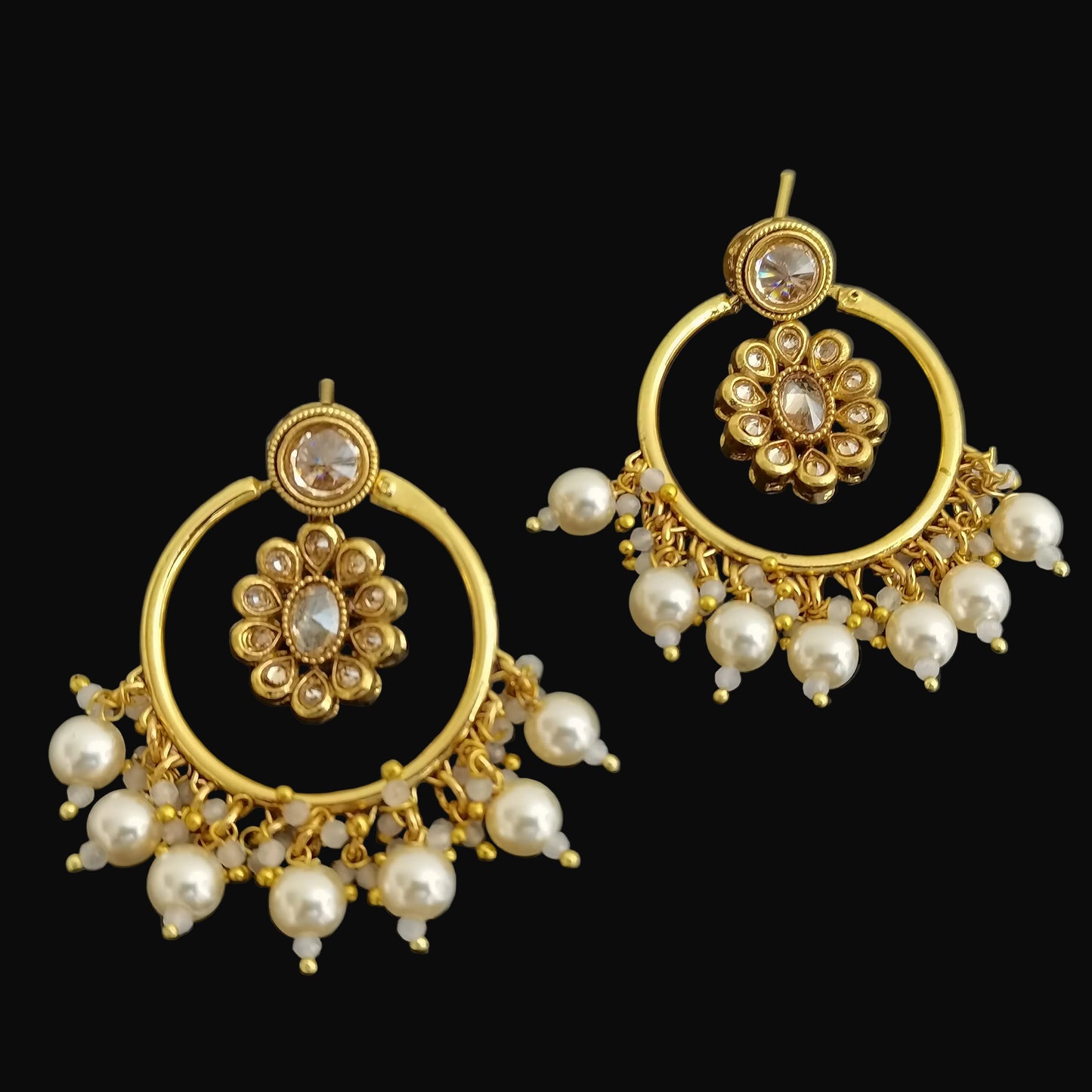 Gold and pearl earrings on a dark background
