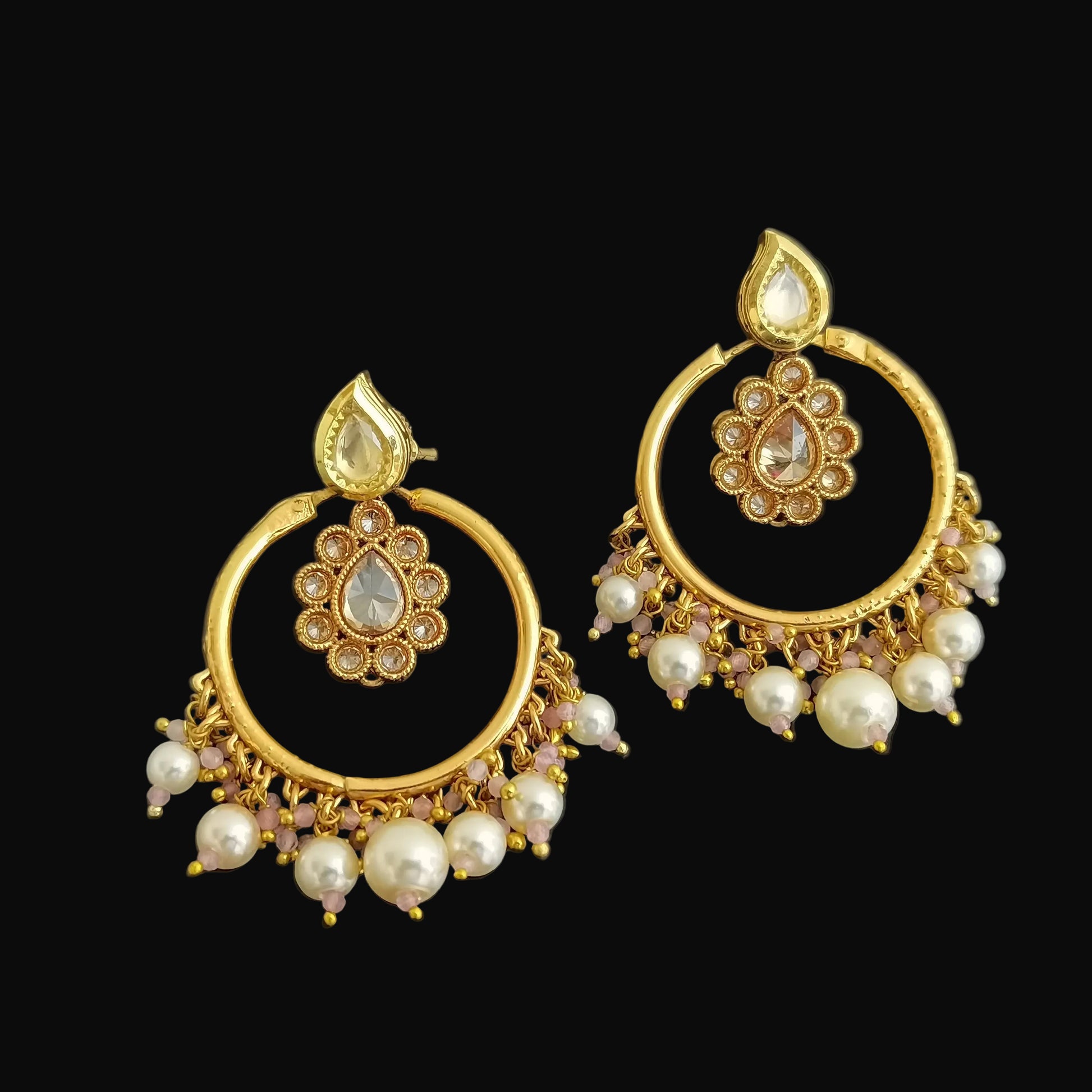 Pair of gold and pearl earrings on a black background