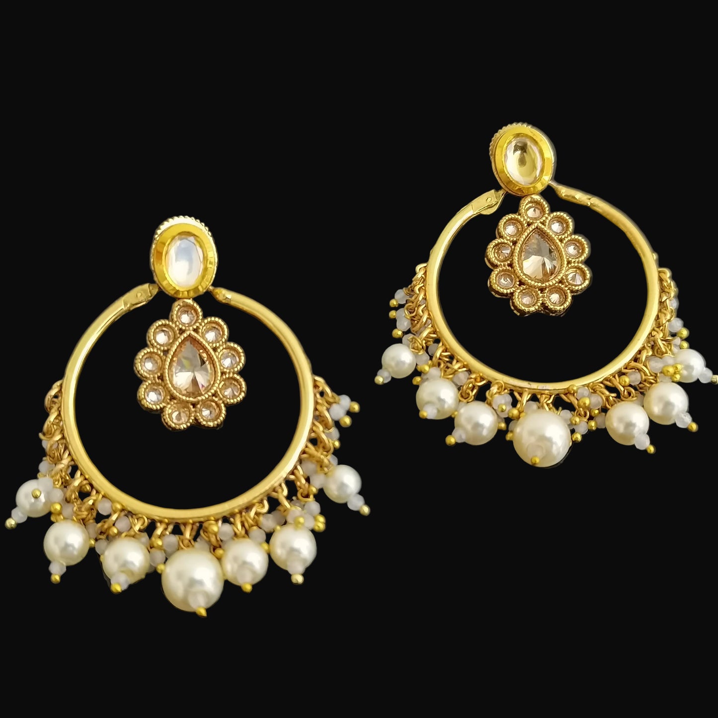 Gold earrings with pearl accents on a black background