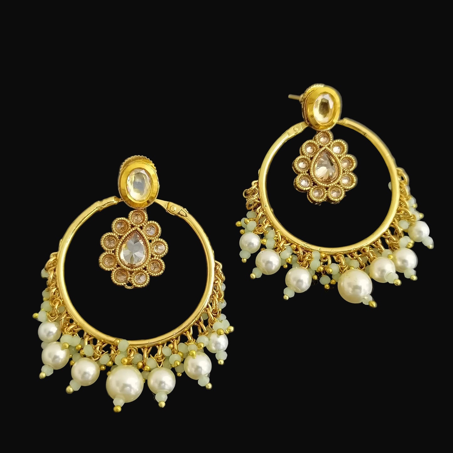 Gold earrings with pearl accents on a black background