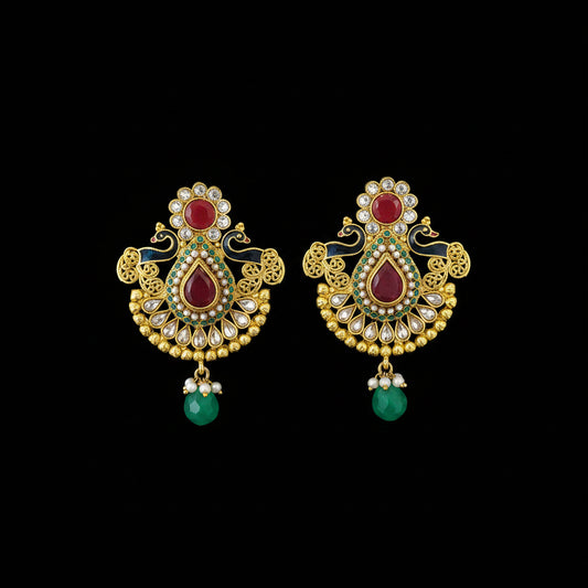 A pair of traditional Indian gold-plated earrings with red stones, green bead drops, and white stone accents, displayed on a dark gray reflective surface with the brand name 'SAHELI MY BEST FRIEND' printed above.