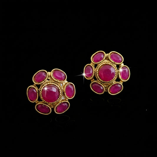 Gold earrings with pink gemstones on a gray background, featuring the brand 'Saheli'.