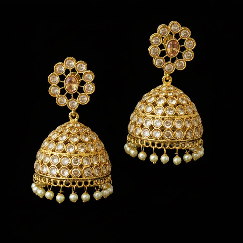 Gold earrings with pearl accents on a gray stand, branded 'Saheli'.