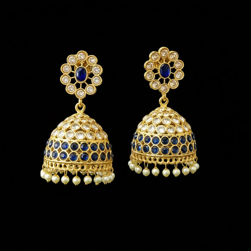 Gold and blue earrings on a gray stand with 'Saheli' branding.