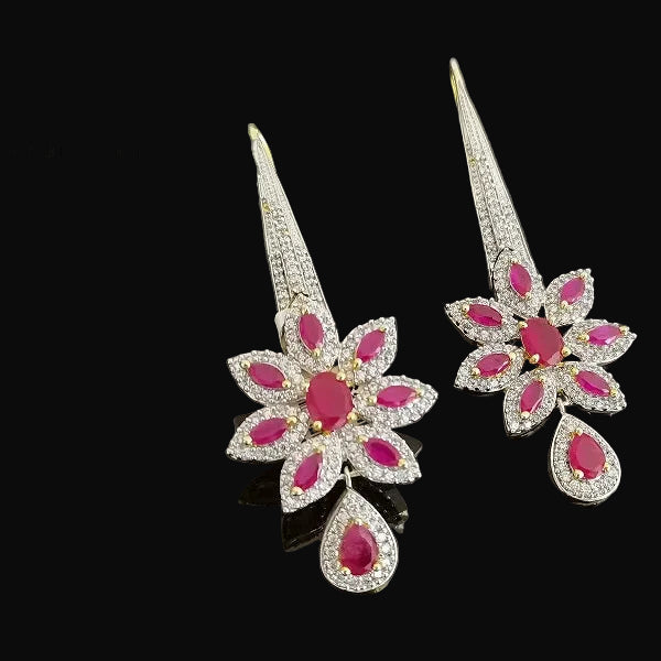 Pair of ornate earrings with pink gemstones on a dark background, branded 'SAHELI'.