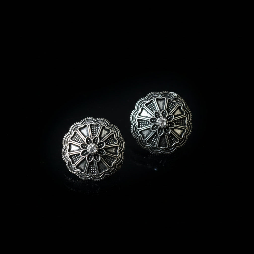 Pair of silver floral earrings on a dark gray background
