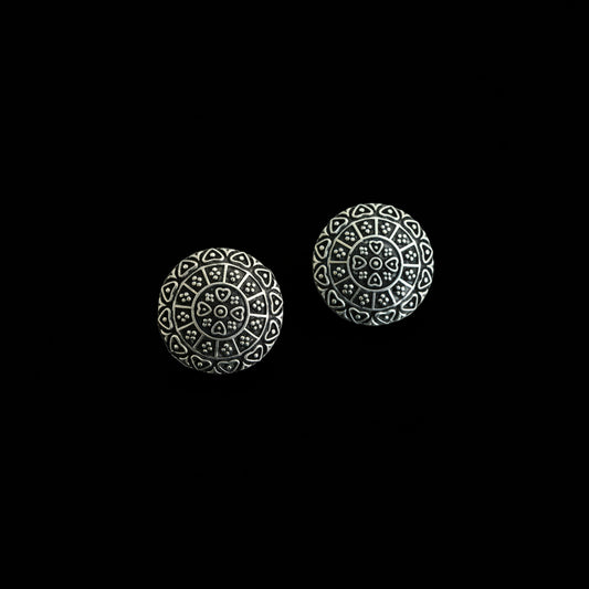 Pair of silver spherical earrings with intricate designs on a dark gray background