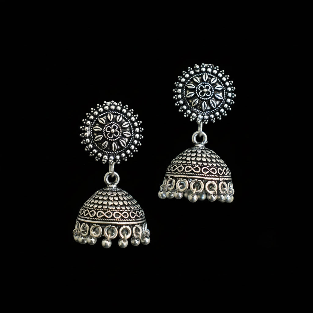 Silver jhumka earrings on a peacock feather