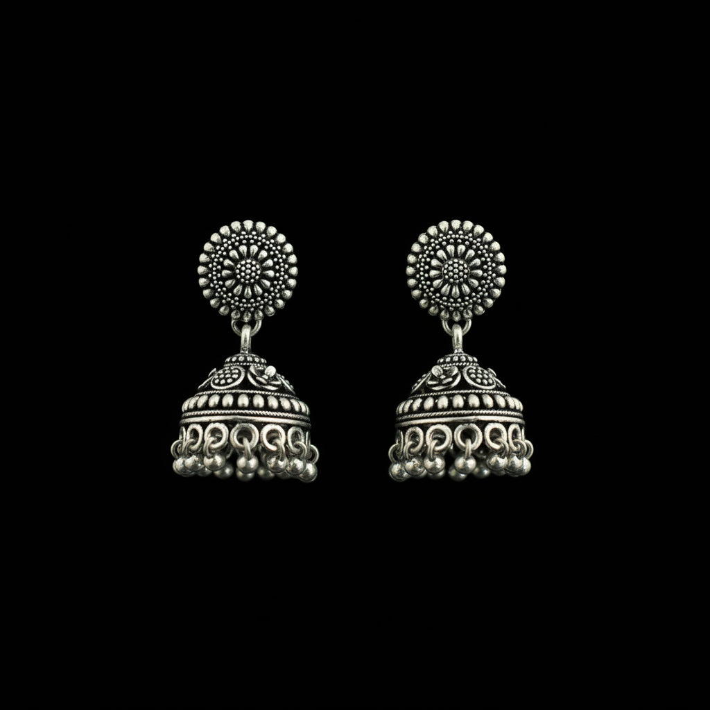Silver earrings on a peacock feather with a gray background