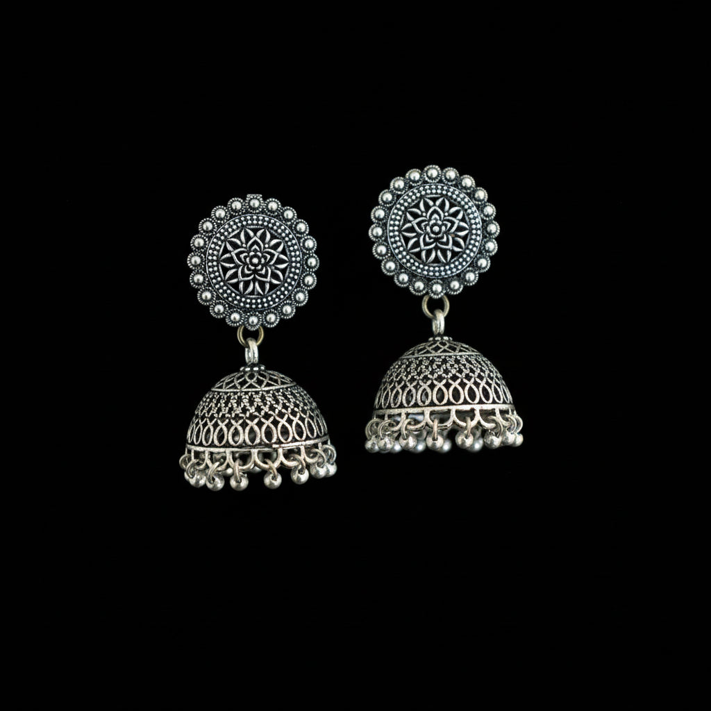Pair of silver jhumka earrings on a decorative background