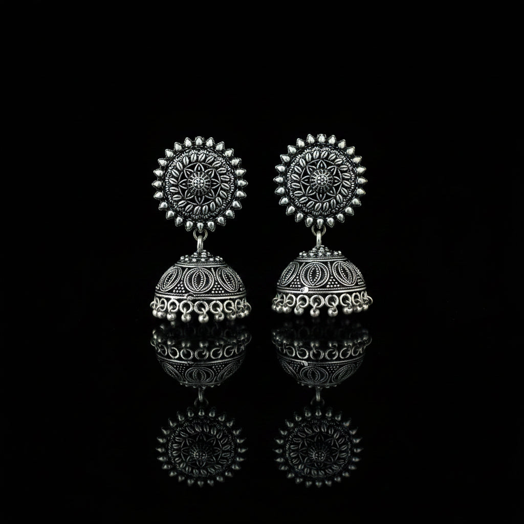 Silver earrings on a peacock feather with a dark background
