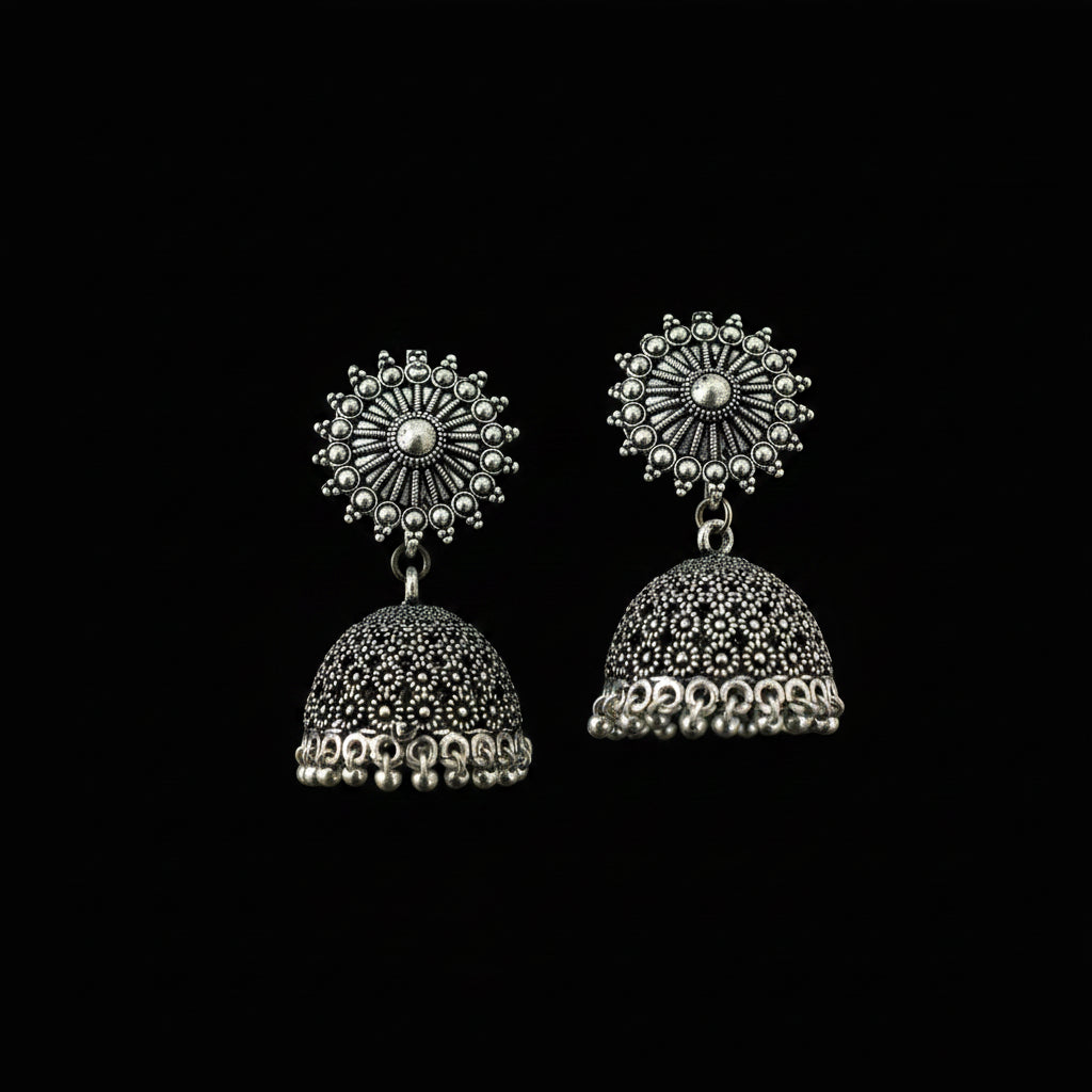 Pair of silver jhumka earrings on a decorative leaf