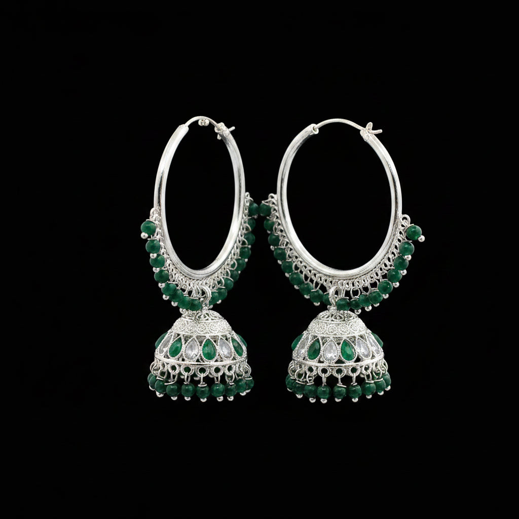 Pair of silver hoop earrings with green gemstones on a black stand against a gray background.