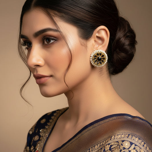 Pair of gold and black earrings with pearl accents on a gray background, branded 'SAHELI'.