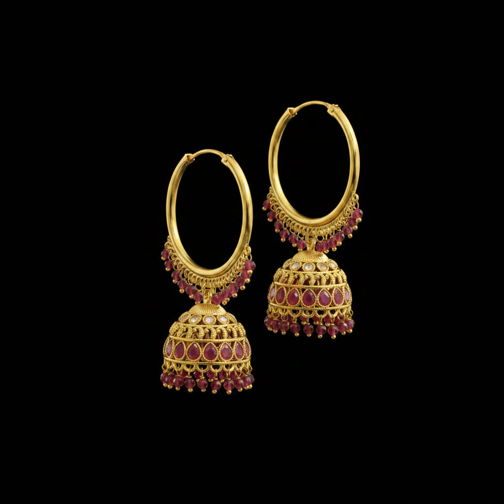 Gold hoop earrings with red gemstones on a gray stand