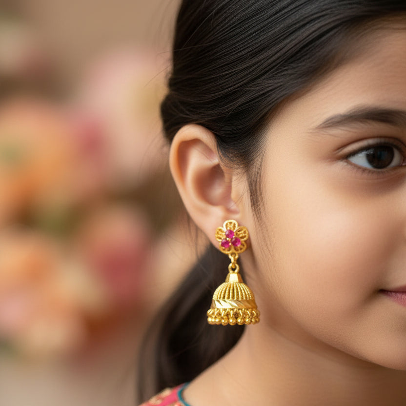 Gold earrings with pink gemstones on a black stand against a gray background