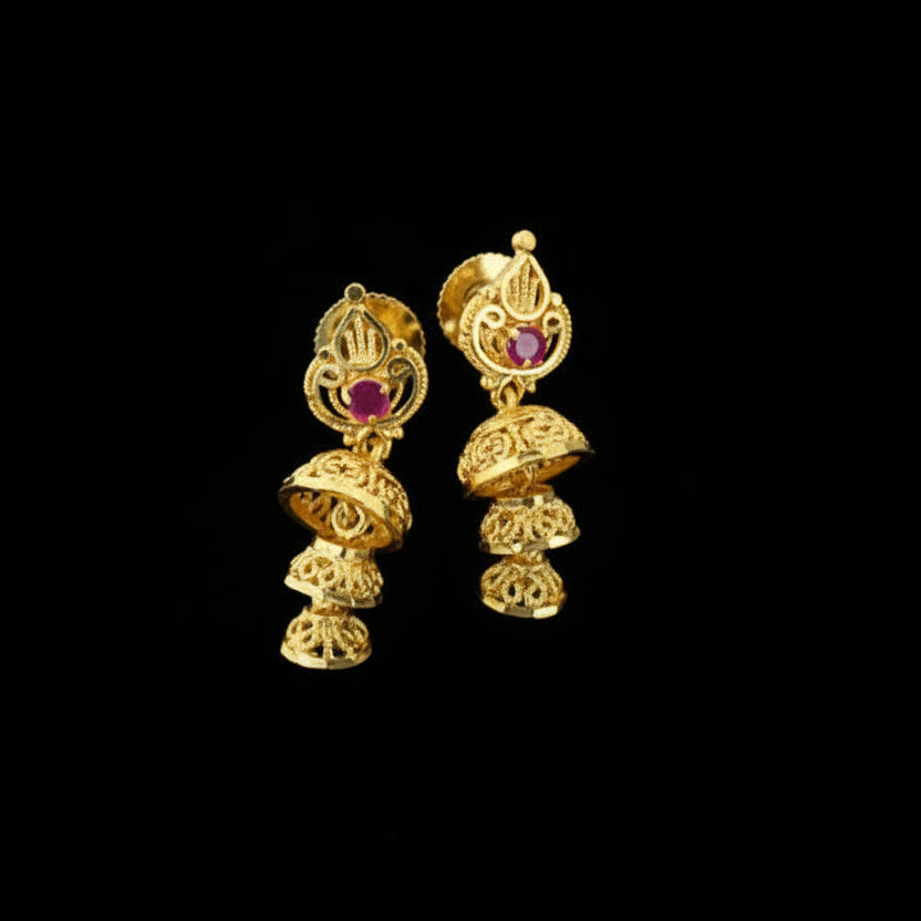 Gold earrings with red gemstones on a black stand against a gray background