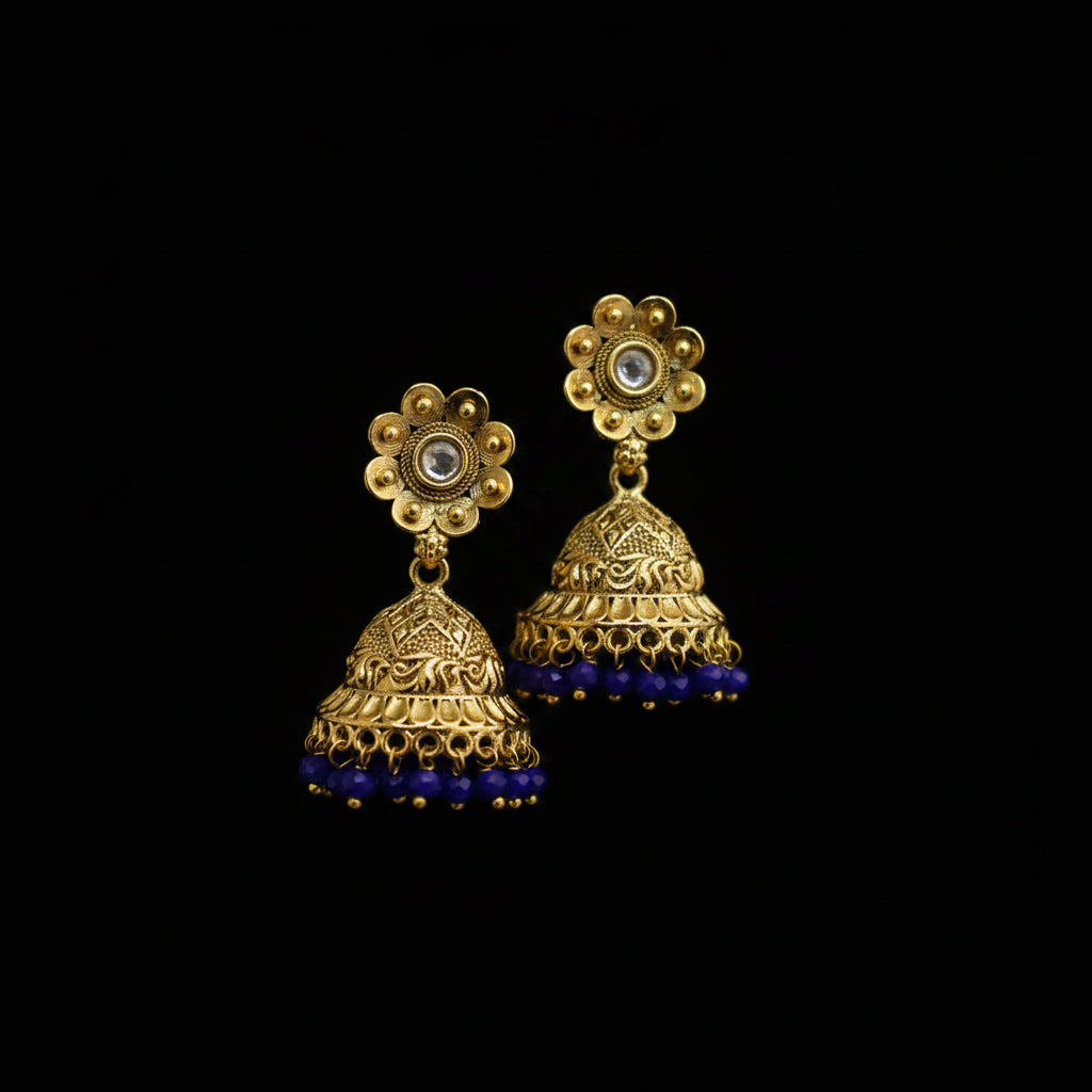 Gold and blue earrings on a gray stand