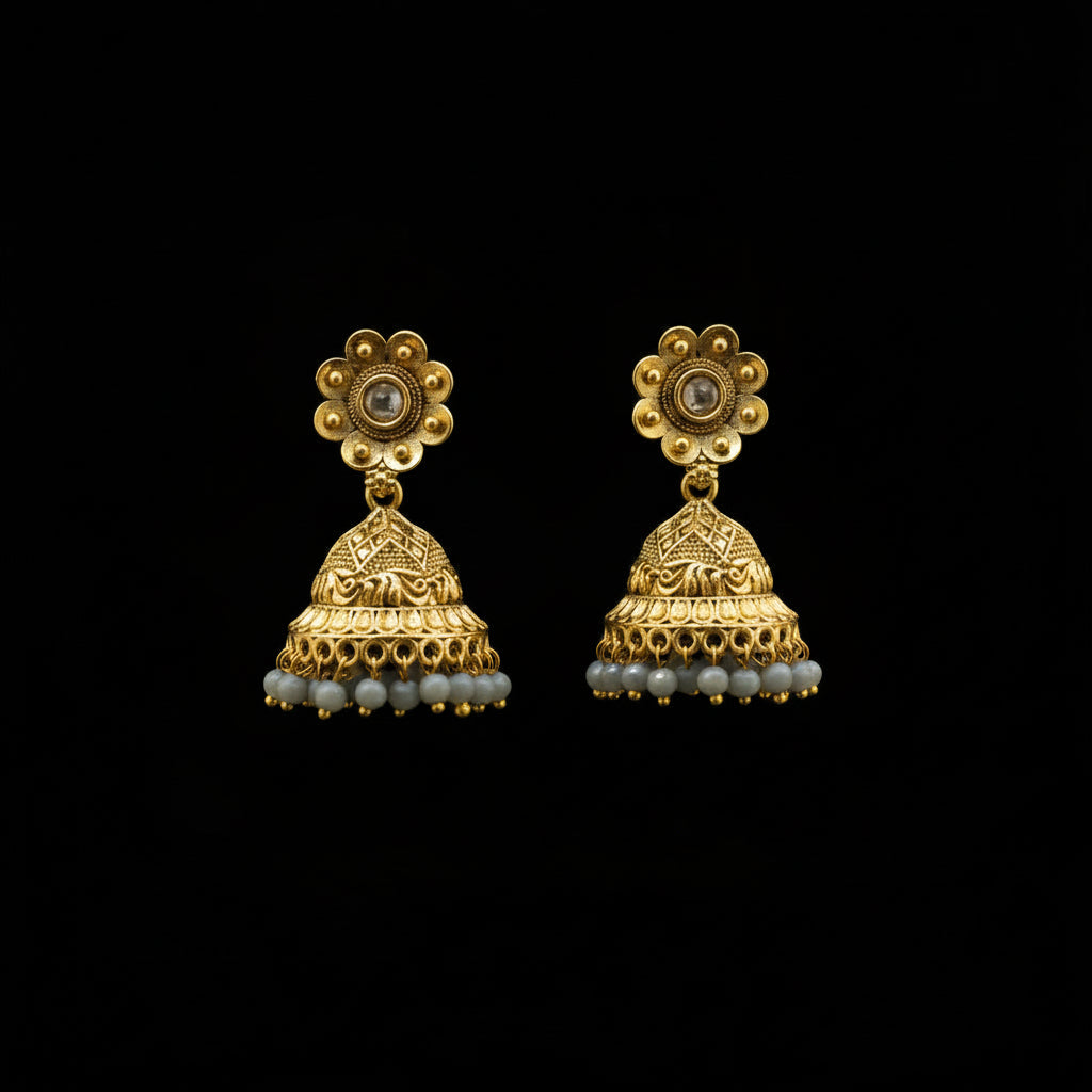 Gold jhumka earrings on a gray stand with a neutral background