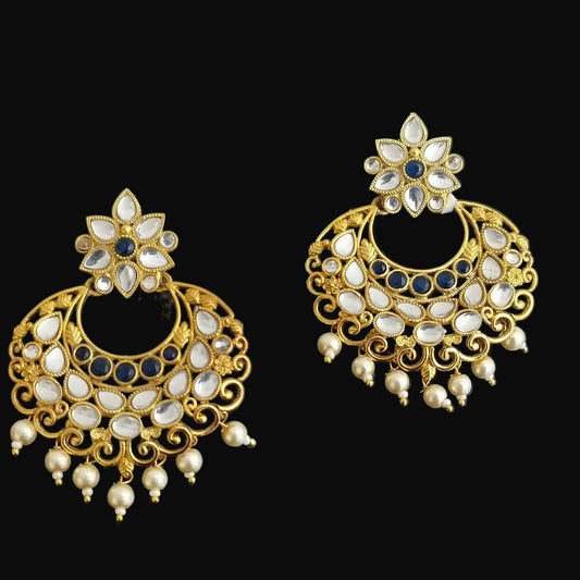Gold earrings with gemstones on a dark background, featuring the brand 'Saheli'.