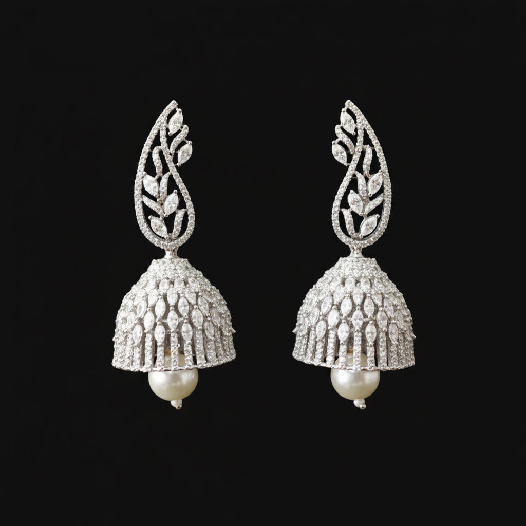 Silver jhumka earrings on a gray stand with 'Saheli' branding.