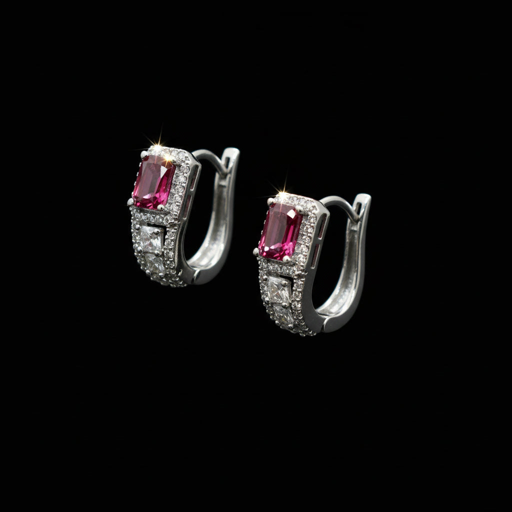 Pair of silver earrings with pink gemstones on a gray background