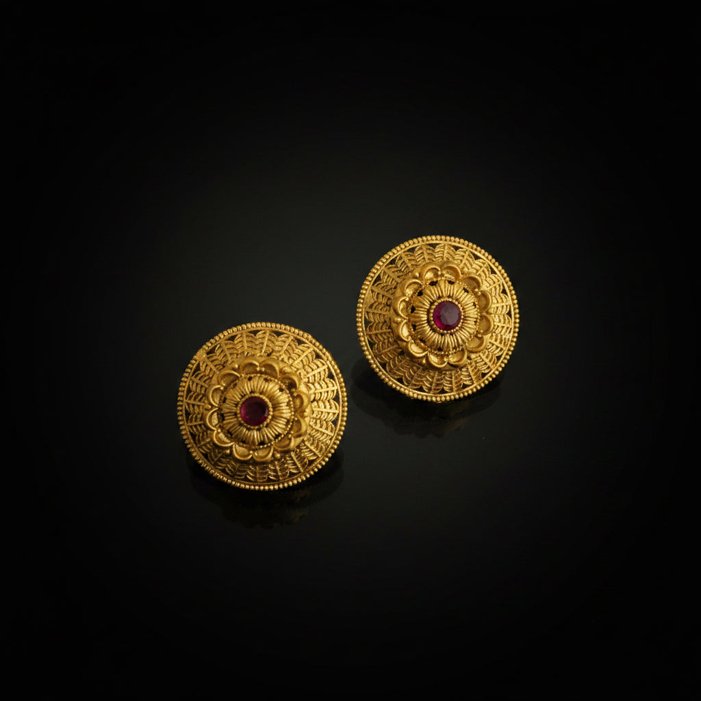 Pair of gold earrings with red gemstones on a black background