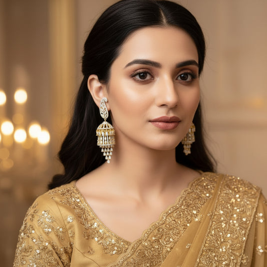Gold and diamond earrings on a gray stand with 'SAHELI' branding.