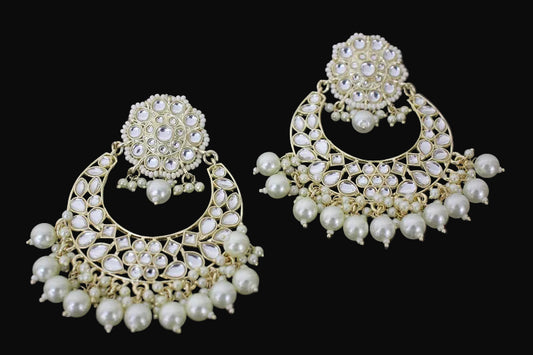 Pair of ornate earrings with pearls on a dark background