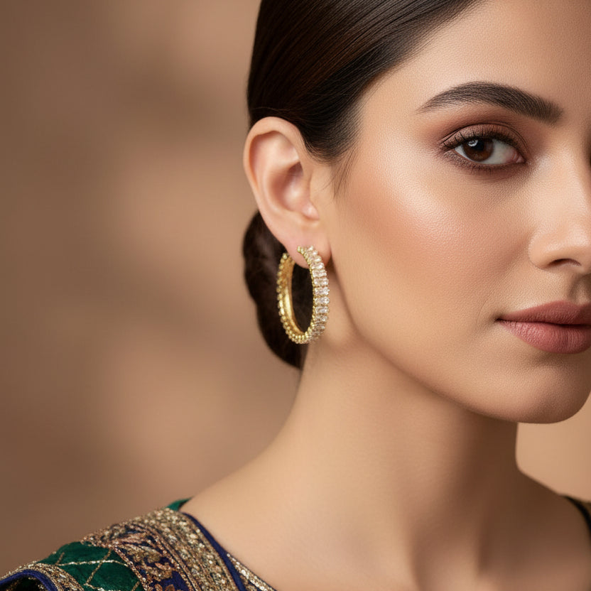 Gold hoop earrings with clear stones on a black background